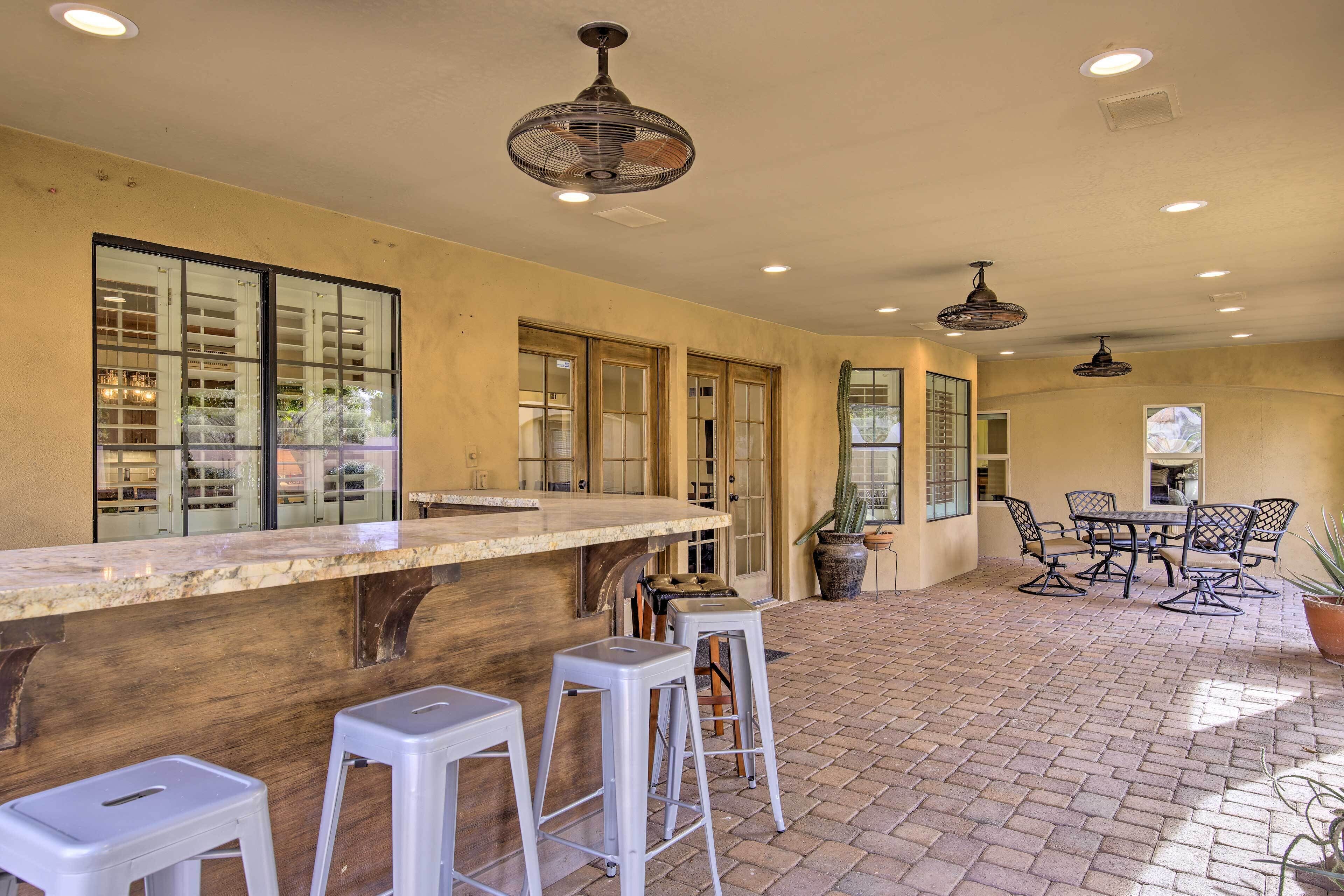 A spacious patio area with a bar counter, seating, and potted plants.