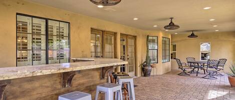 A spacious patio area with a bar counter, seating, and potted plants.