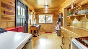 A wooden cabin interior with a kitchen area, a dining table, and a workspace. - Large Deck, Grill: Pet-friendly Show Low Retreat! (Show Low)