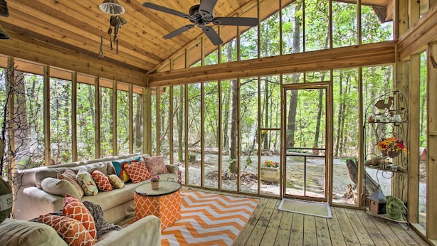 A wooden deck with a sofa and chairs, large windows, and a ceiling fan. - Enchanting 'whitney Cabin' w/ Beach & Creek! (Kiln)