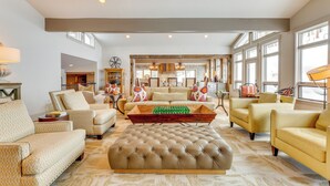 Ein geräumiges Wohnzimmer mit einem großen, gesteppten Ottomanen, mehreren Sofas und einem Holztisch.