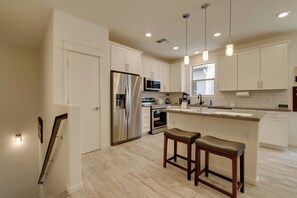 A modern kitchen with white cabinets, stainless steel appliances, and a central island with bar stools.