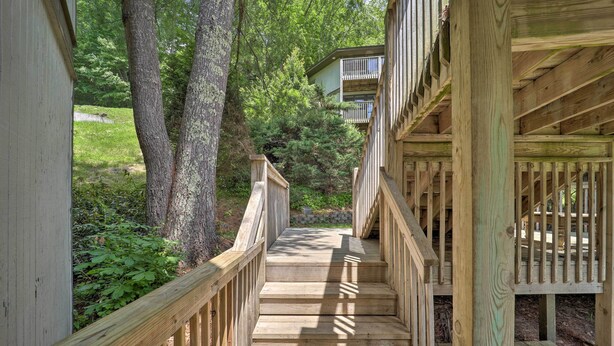 Un escalier en bois mène à un bâtiment entouré d’arbres.
