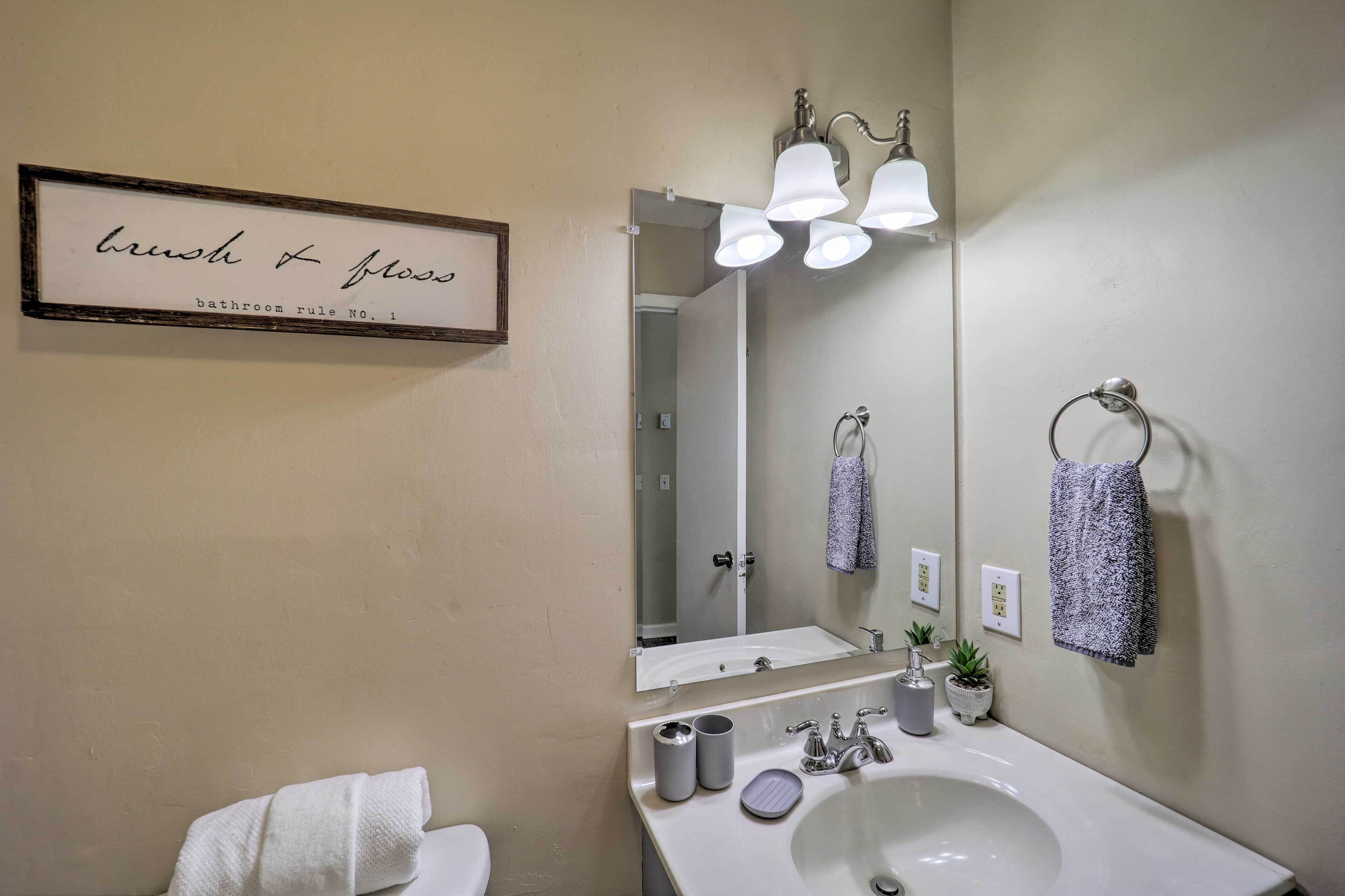 Une salle de bain équipée d’un lavabo, d’un miroir, d’un porte-serviettes et d’une pancarte indiquant « se brosser les dents et utiliser le fil dentaire », ainsi que les règles à respecter dans la salle de bain.