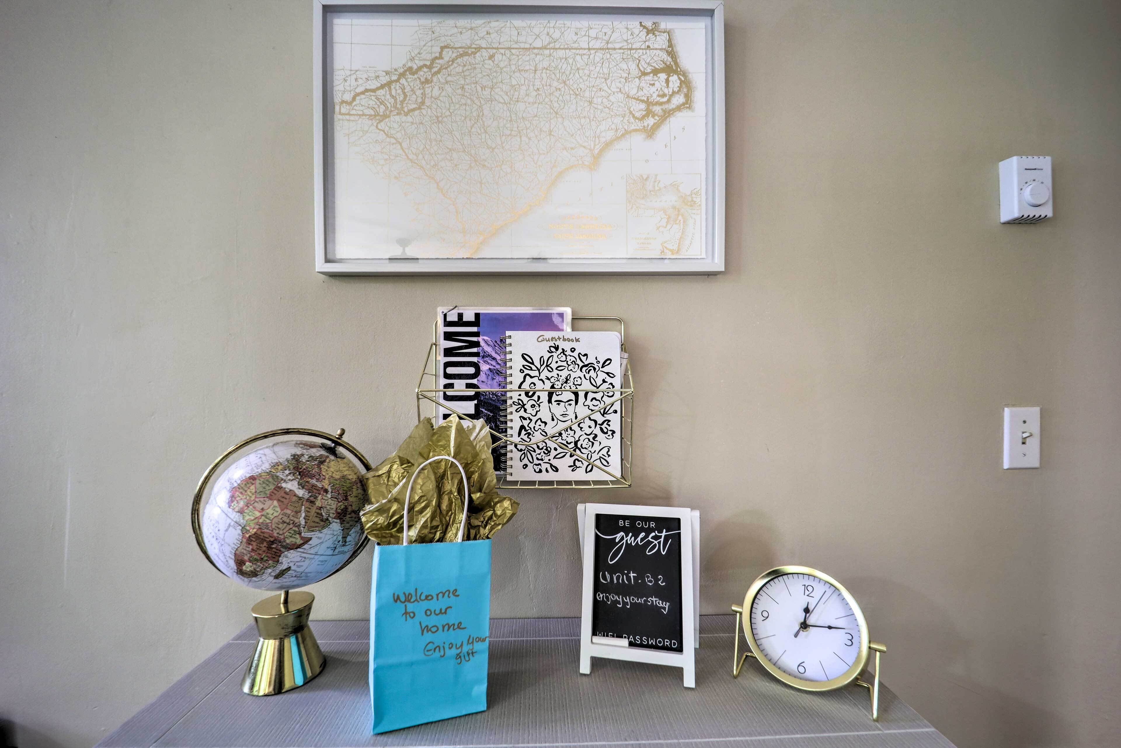 Eine Wand mit einer gerahmten Karte, einem Globus, einer Reisegasttasche, einem Gästebuch, einer Kreidetafel und einer Uhr.