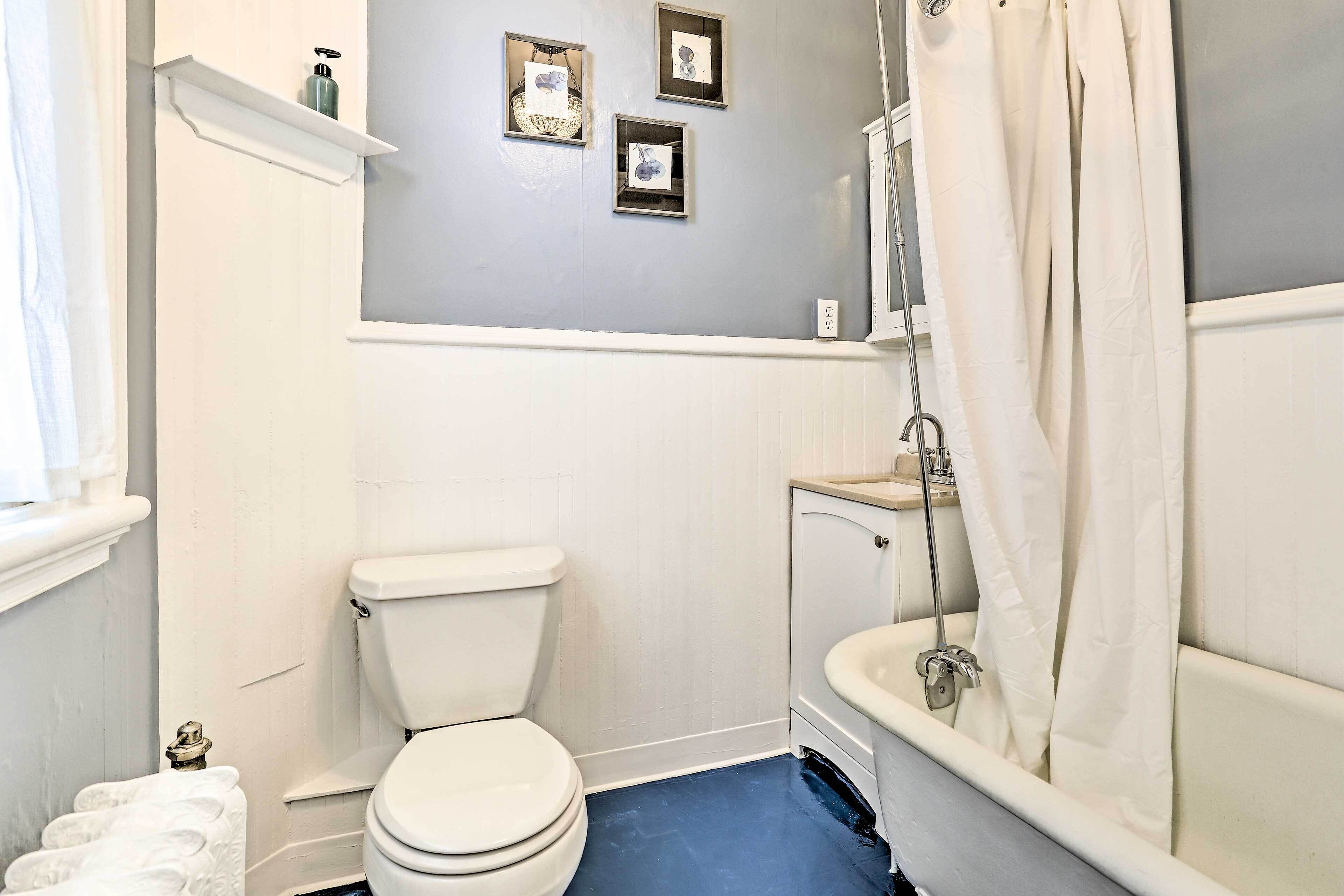A bathroom with a white toilet, a bathtub with a shower curtain, and a blue floor.