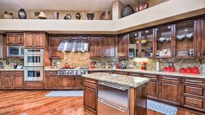 A spacious kitchen with dark wood cabinets, stainless steel appliances, and a granite countertop. - Lavish Estate w/ Sports Court & Home Theater! (Scottsdale)