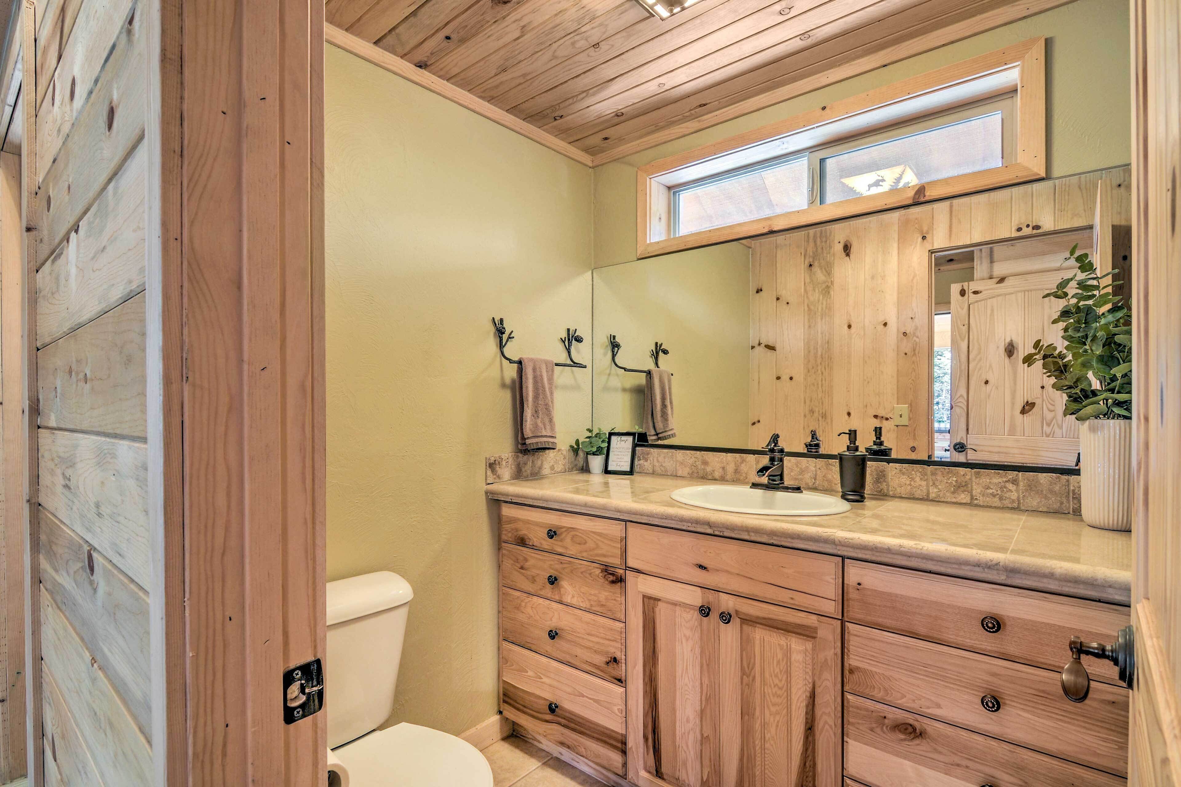 A wooden-paneled bathroom with a large mirror, a sink, and a toilet.