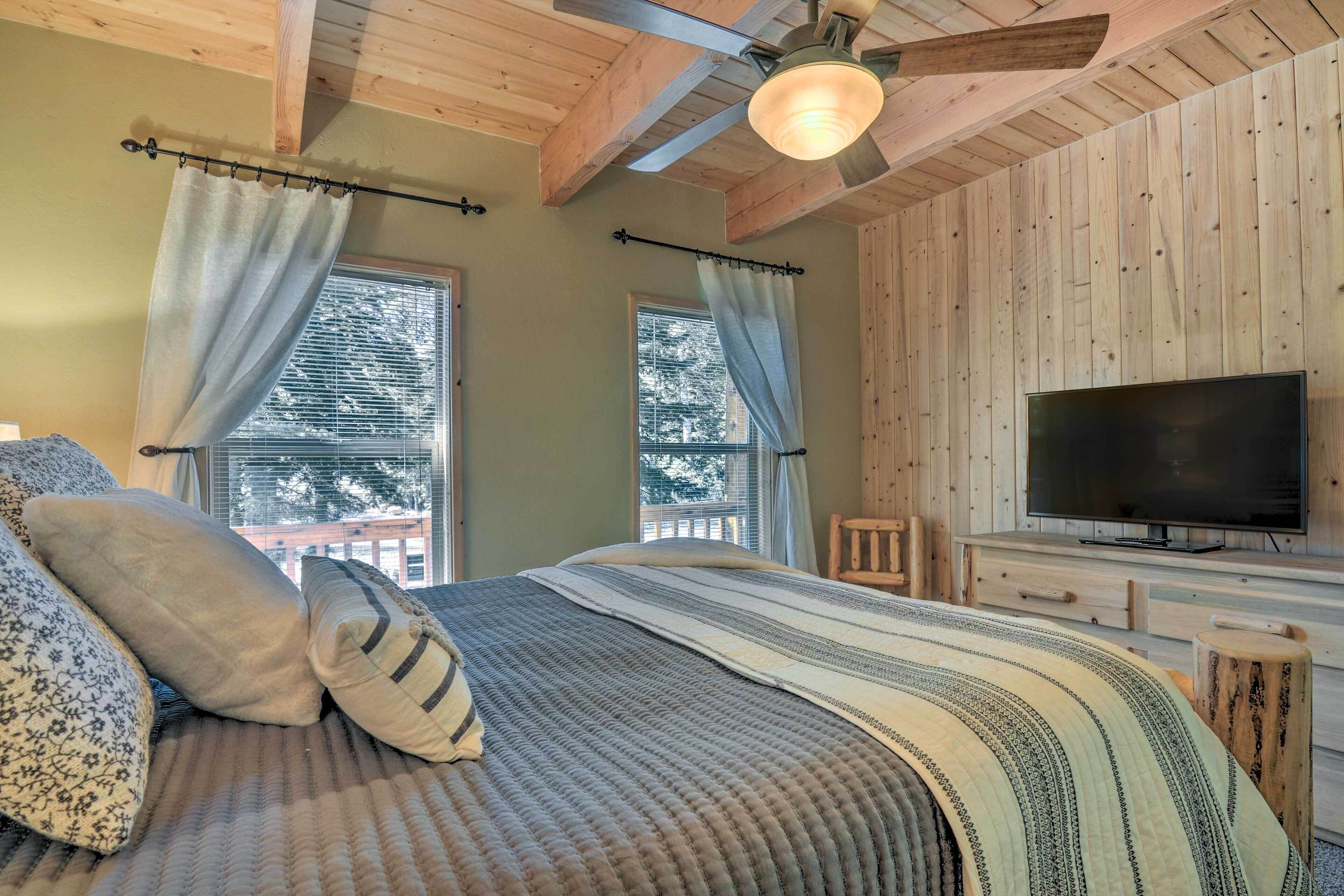 A bedroom with a large bed, a television, and wooden walls.