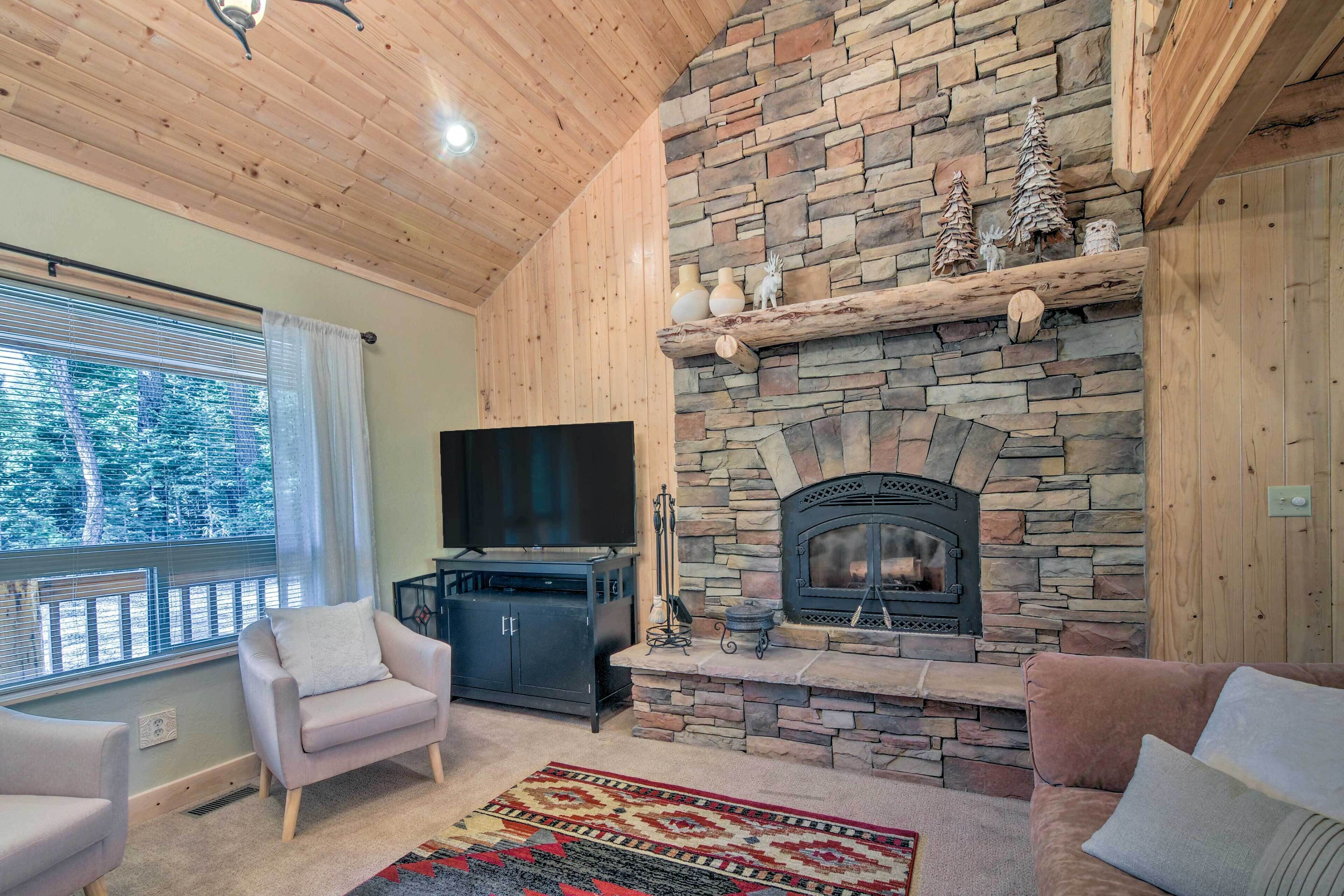 A cozy living room with a stone fireplace, a flat-screen TV, and comfortable seating.