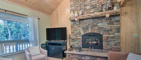 A cozy living room with a stone fireplace, a flat-screen TV, and comfortable seating.