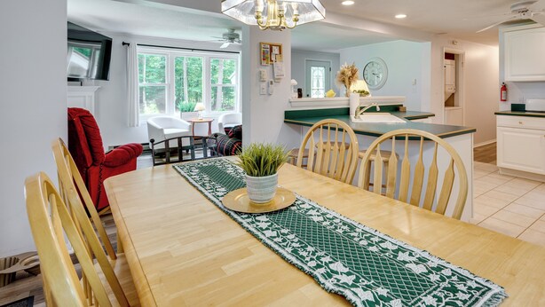 Un coin repas avec une table en bois, des chaises, une plante en pot et un chemin de table à motifs.