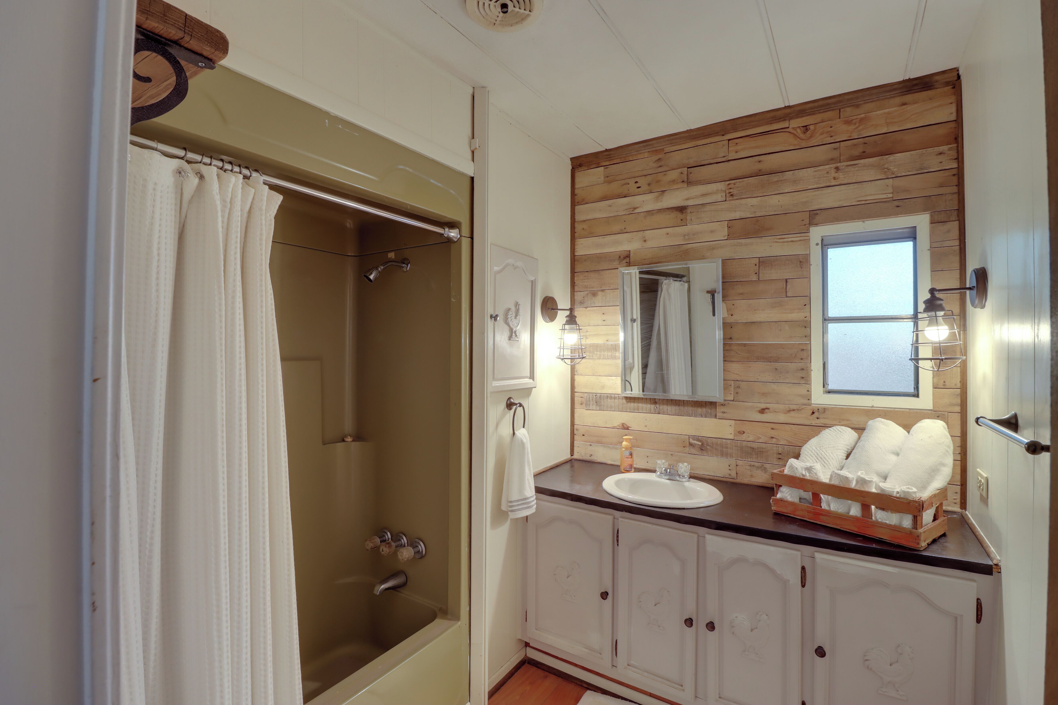 A bathroom with a wooden vanity, a shower, and a mirror.