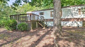A mobile home with a wooden deck and a staircase leading to the entrance. - Edgemont Home w/ Deck ~ 9 Mi to Greers Ferry Lake! (Edgemont)