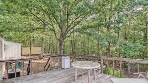 A wooden deck with a table and chairs, surrounded by trees. - Edgemont Home w/ Deck ~ 9 Mi to Greers Ferry Lake! (Edgemont)
