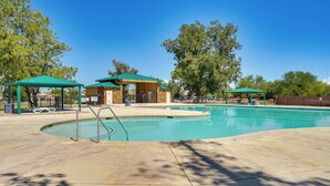A swimming pool with a green-roofed pavilion, a covered seating area, and a stone building in the background. - Step-free Sahuarita Retreat! Patio + Pool Access (Sahuarita)
