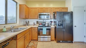 A kitchen with wooden cabinets, stainless steel appliances, a double sink, and a window providing natural light. - Step-free Sahuarita Retreat! Patio + Pool Access (Sahuarita)