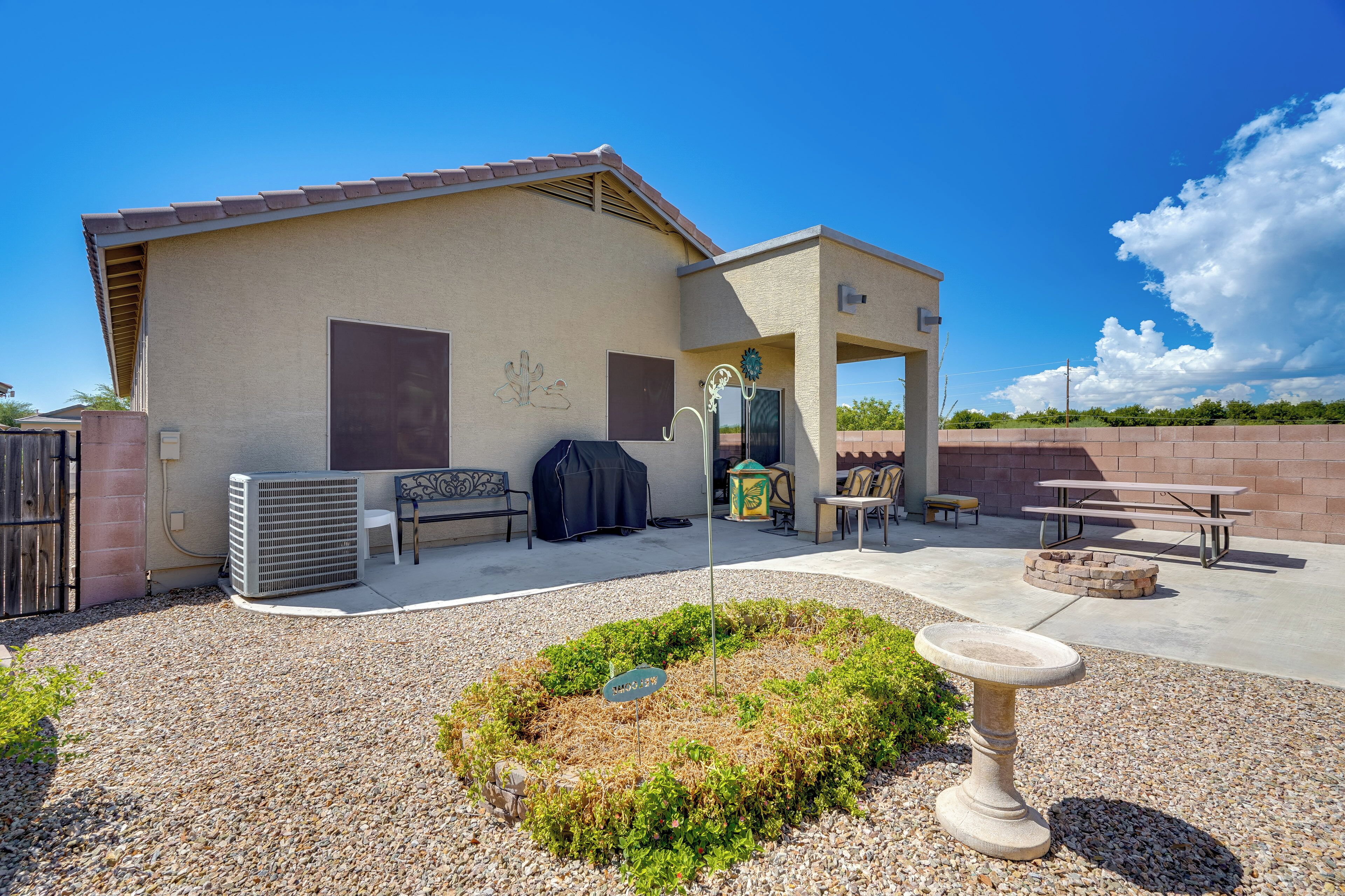 A residential backyard with a patio, outdoor seating, and a decorative birdbath.