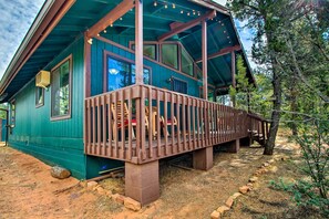 Een houten vakantiehuis met terras, grote ramen en een onverharde oprit.
