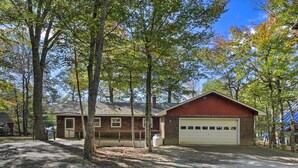 A single-story building with a garage, surrounded by trees. - Lakefront Home With Deck, Dock, & Water Access! (Liberty)