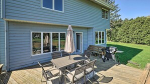 Une maison bleue avec une terrasse, du mobilier d’extérieur et un barbecue.