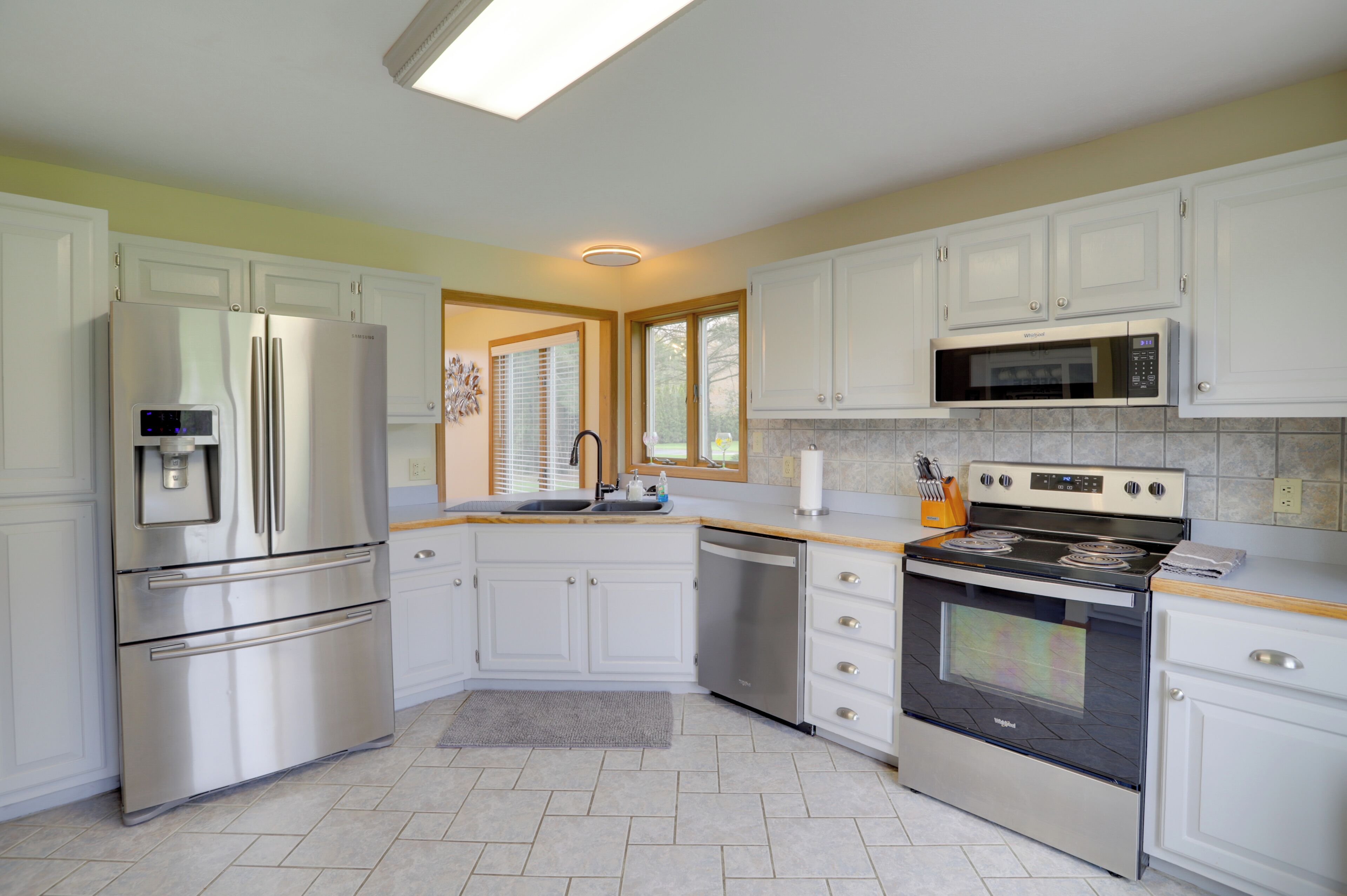 A modern kitchen with white cabinets, stainless steel appliances, a dishwasher, and a built-in oven.