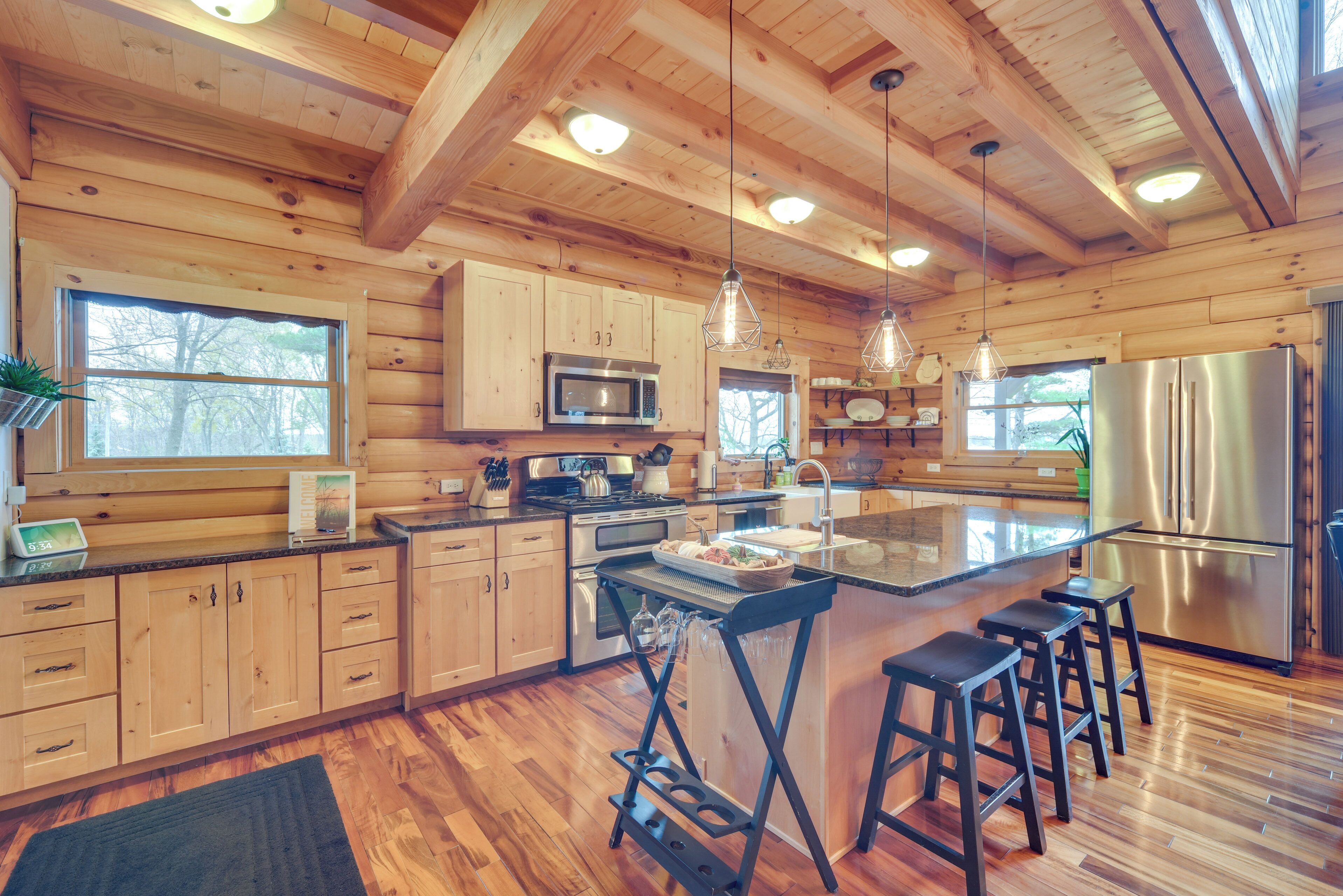 A spacious kitchen with wooden cabinets, a stainless steel refrigerator, and a large island with bar stools.
