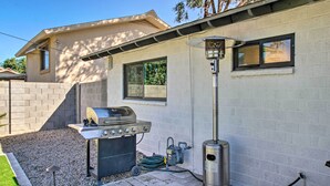 A backyard with a barbecue grill, a gas pump, and a tall lamp post.