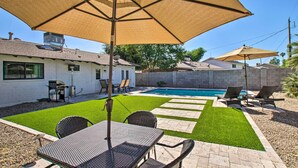 A backyard with a swimming pool, patio furniture, and a large umbrella.