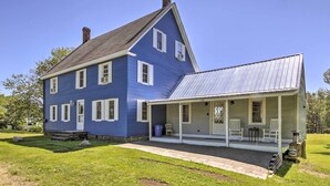 A two-story blue house with a covered porch and a metal roof. - Riverfront Coastal Escape With Deep Water Dock! (Wiscasset)