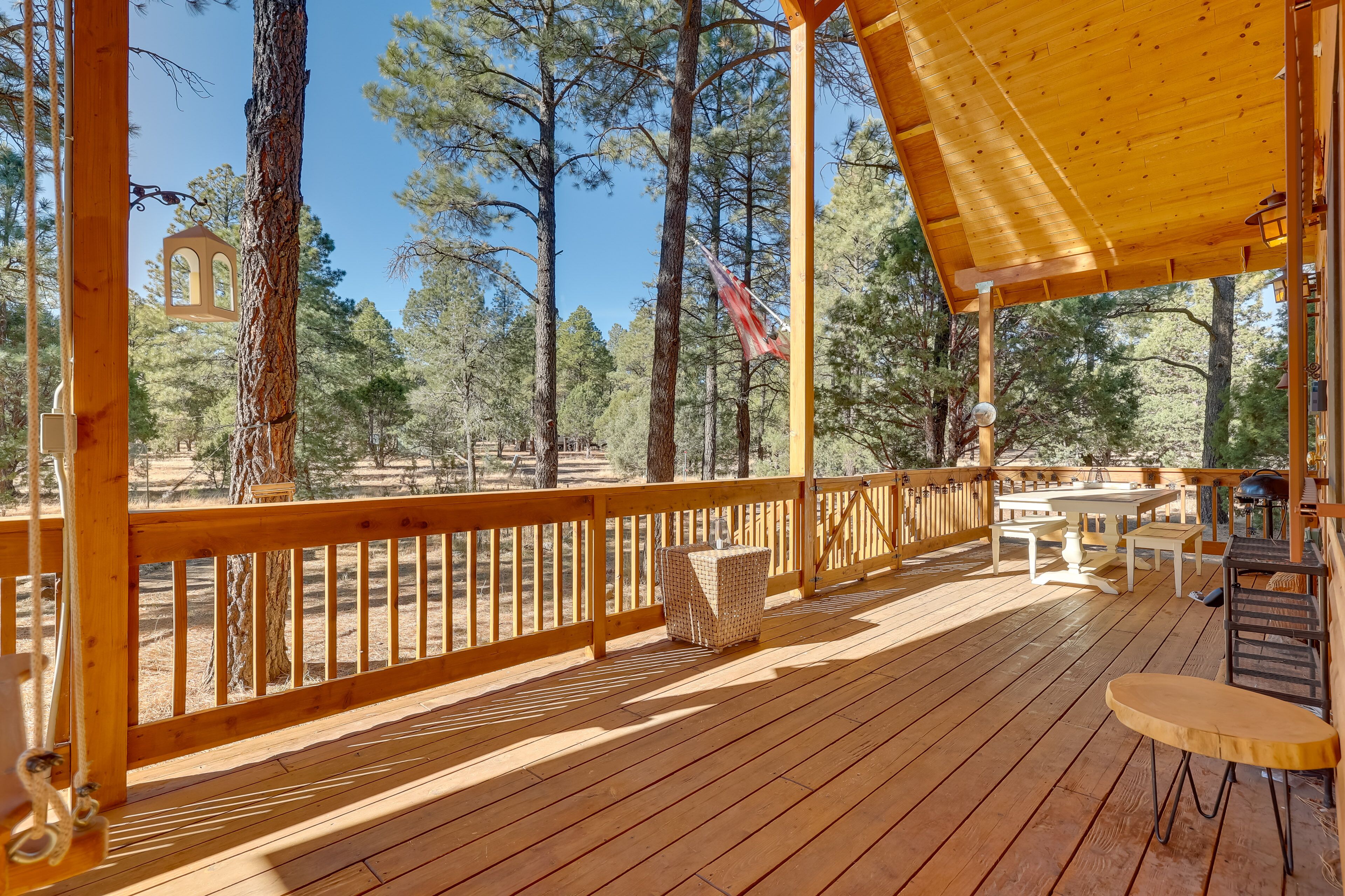 A wooden deck with a railing, tables, and chairs.