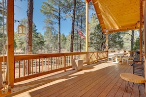 A wooden deck with a railing, tables, and chairs. - Dog-friendly Nutrioso Cabin w/ Wraparound Porch! (Eagar)