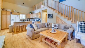 Amplia sala de estar con escalera de madera, cocina con armarios de madera y un letrero que dice "HALL".