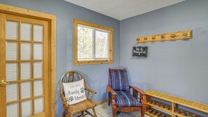 A room with a wooden door, a window with blinds, two wooden chairs, a shelf, and a wall sign. - Powell Lake 'UP Badger Lodge Bnb' w/ Shared Dock (Wetmore)