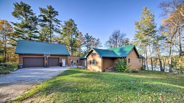 A two-story building with a green roof, a garage, and a basketball hoop in front. - Powell Lake 'UP Badger Lodge Bnb' w/ Shared Dock (Wetmore)