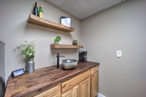 A kitchen with wooden cabinets, a stone bowl sink, a coffee machine, and a small potted plant.