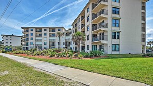 A multi-story residential building with balconies, a landscaped lawn, and a clear sky. - Oceanfront Ormond Beach Getaway w/ Balcony! (Ormond Beach)