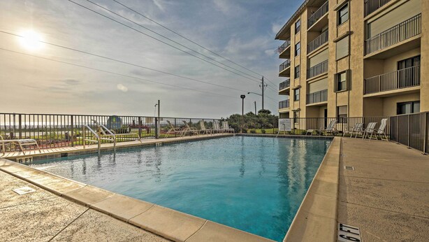 A swimming pool with a clear blue water, surrounded by a concrete deck and a metal railing. - Oceanfront Ormond Beach Getaway w/ Balcony! (Ormond Beach)