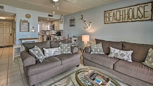 A living room with two grey sofas, a coffee table, and a ceiling fan. A sign on the wall reads "BEACHHOUSE". - Oceanfront Ormond Beach Getaway w/ Balcony! (Ormond Beach)