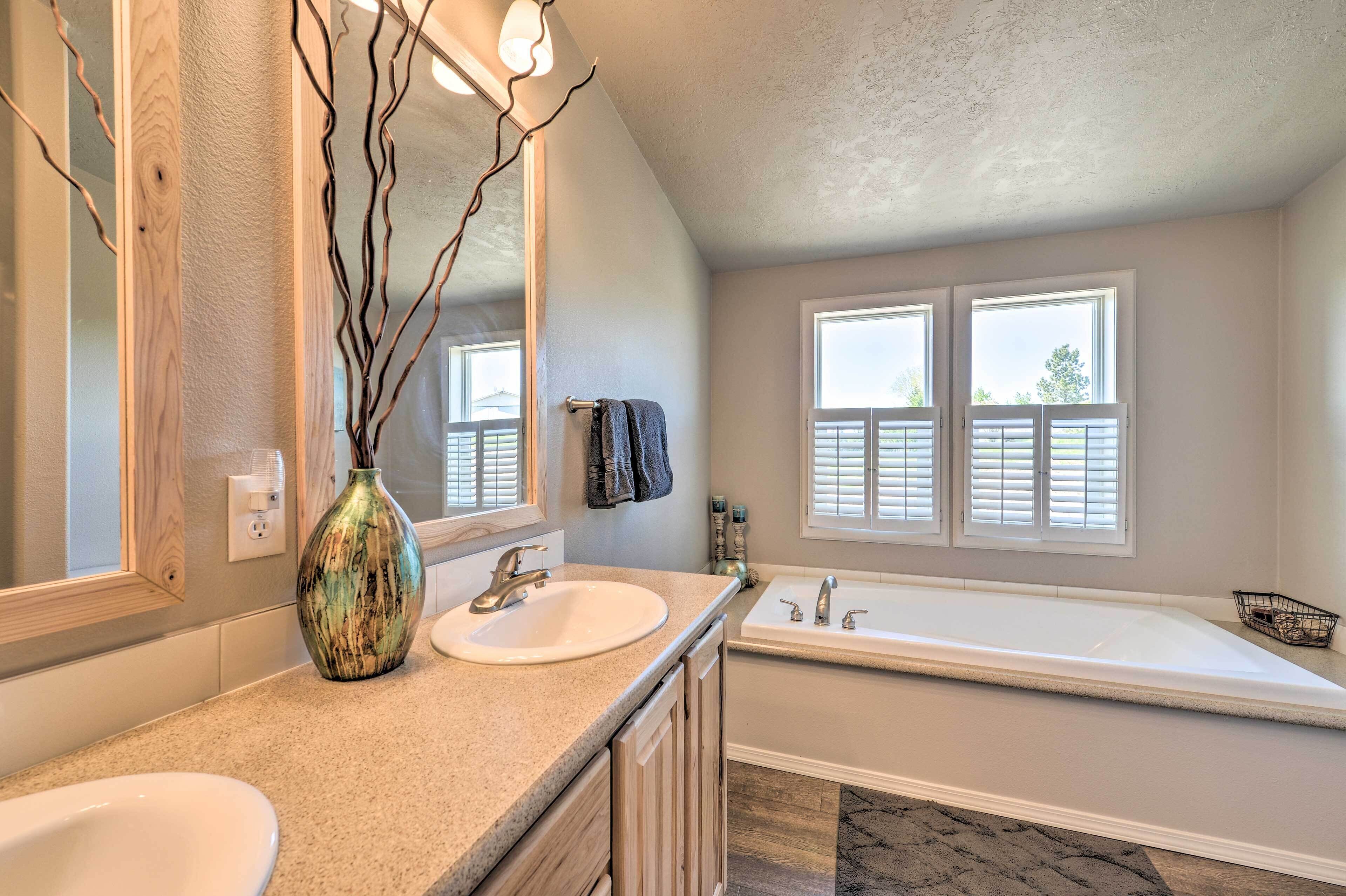 A bathroom with a sink, mirror, vanity, and bathtub.