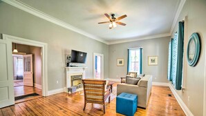 Un salon spacieux doté de planchers en bois franc, d’un ventilateur de plafond, d’une cheminée, d’un téléviseur et d’un canapé.