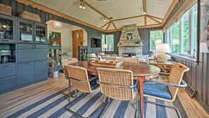 A spacious dining area with a large wooden table, wicker chairs, and a stone fireplace. - Lake Michigan Hideaway: Pool, Steps to Beach! (New Buffalo)