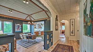 A spacious kitchen with wooden cabinets, a dining area with a striped rug, and a view of the outdoors. - Lake Michigan Hideaway: Pool, Steps to Beach! (New Buffalo)
