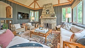 A cozy living room with a stone fireplace, comfortable seating, and large windows. - Lake Michigan Hideaway: Pool, Steps to Beach! (New Buffalo)