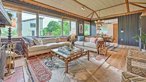 A spacious living room with a large sofa, a coffee table, and a dining area with a table and chairs. - Lake Michigan Hideaway: Pool, Steps to Beach! (New Buffalo)