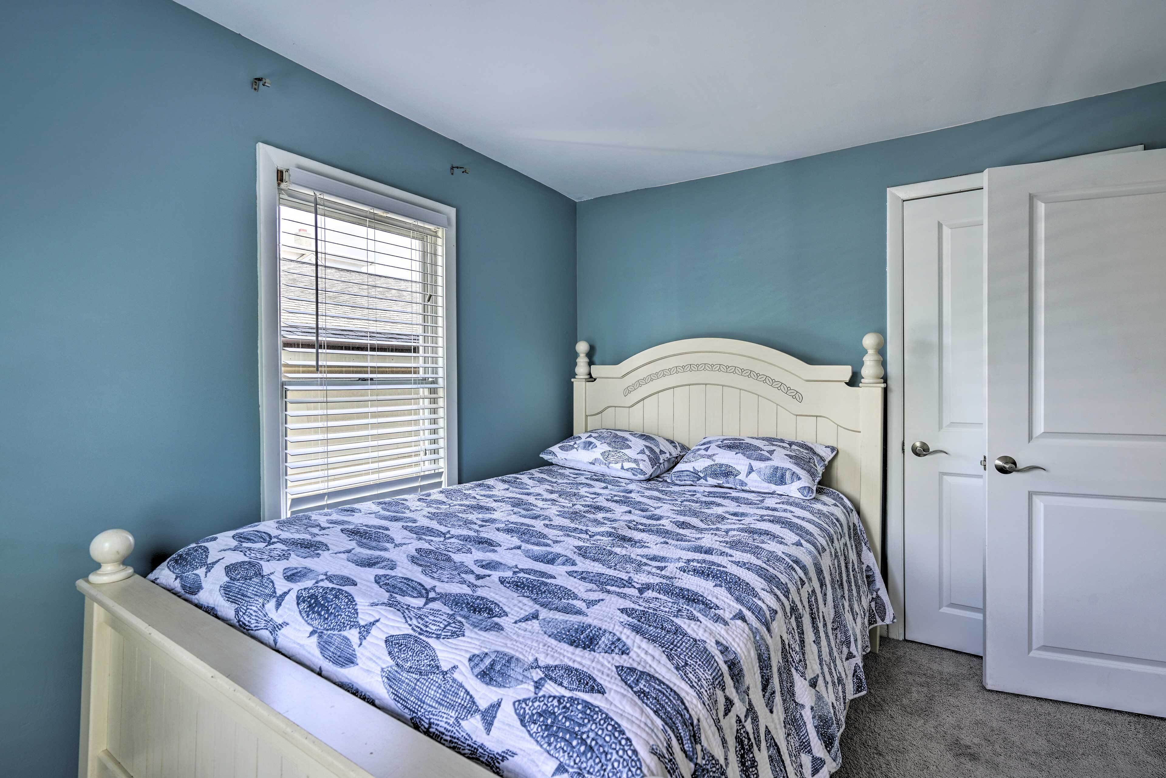 A bedroom with a bed, a window with blinds, and a door.
