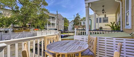 Une terrasse en bois avec une table ronde et des chaises, entourée d’une clôture blanche.