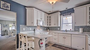 A kitchen with white cabinets, a granite countertop, and a backsplash. - Charming Ocean City Townhome: Walk to Beach! (Ocean City)