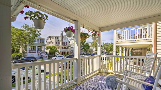 A porch with white railings, hanging flower pots, and a patterned rug. - Charming Ocean City Townhome: Walk to Beach! (Ocean City)