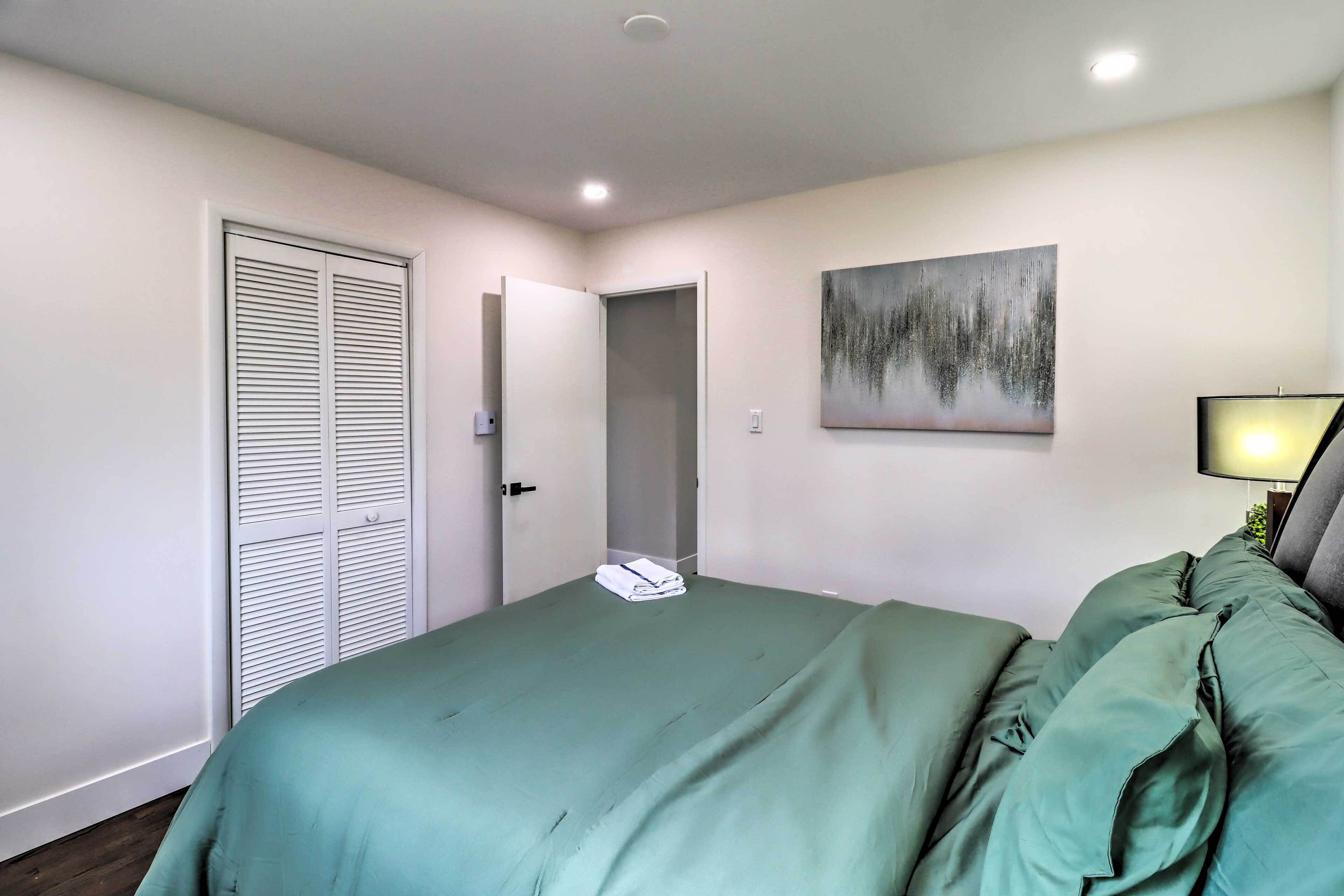 Un dormitorio con cama, armario, puerta y una lámpara fijada a la pared.